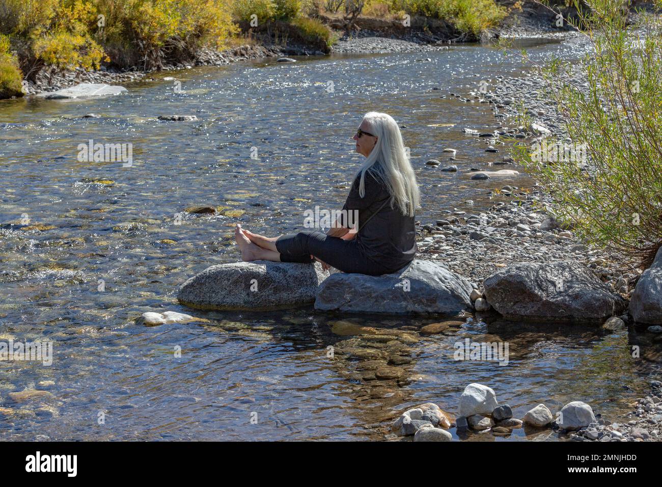 USA, Idaho, Sun Valley, Seniorblonde, die Stein für Fluss sitzt Stockfoto