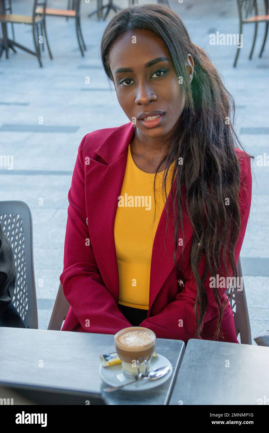 Attraktive afroamerikanische Geschäftsfrau macht eine Kaffeepause. Sie schaut in die Kamera Stockfoto