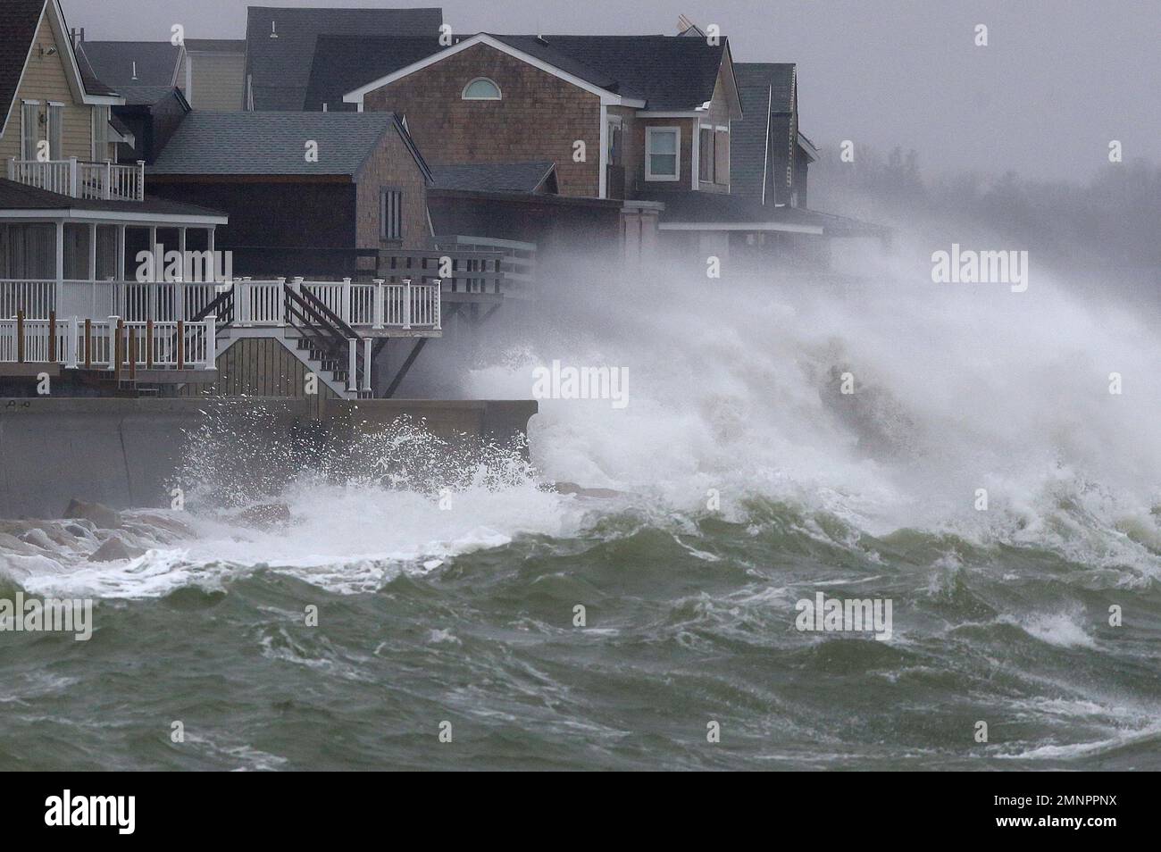 Waves crash against a seawall and houses, Wednesday, March 7, 2018, in
