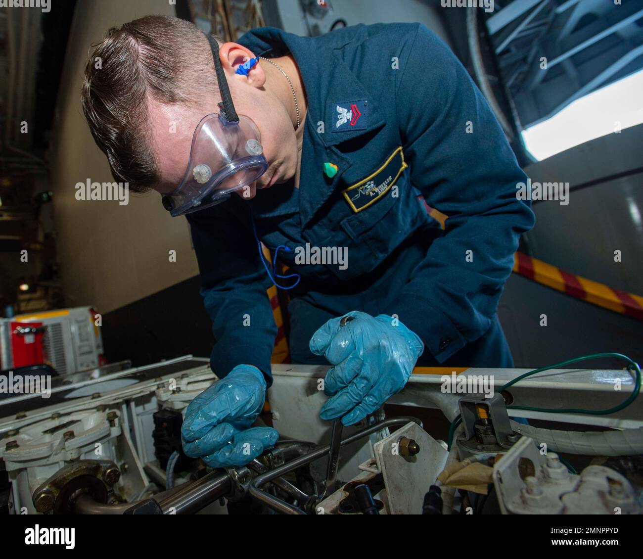 221004-N-NX635-1057 PAZIFIK. (3. Oktober 2022) USA Navy Aviation Structural Mechanic 2. Class Asher Wheeler aus Fredricksburg, W.A., verwendet ein Paar Schraubenschlüssel, um einen Satz Ventile von einem Auffangwagen in der Hangarbucht an Bord des Flugzeugträgers USS Nimitz (CVN 68) zu entfernen. Die Nimitz Carrier Strike Group bereitet sich auf einen bevorstehenden Einsatz vor. Stockfoto