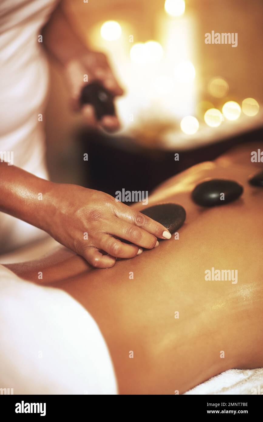 Finden Sie die richtige Massage für Sie. Eine junge Frau, die eine Hot-Stone-Massage bekommt. Stockfoto
