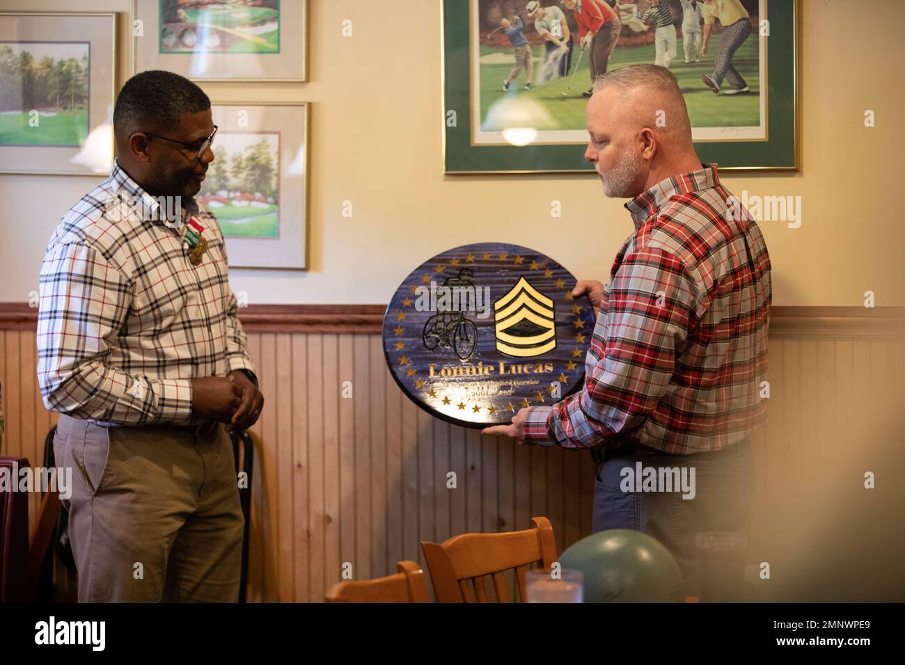 Sgt. 1. Klasse Lonnie Lucas, der Notarzt der Illinois Army National Guard, wird eine Ruhestandsplakette vom pensionierten Kommando Sgt. Maj. Paul Kindred während einer Ruhestandsfeier am 7. Oktober 2022 bei Mario’s Pizza in Springfield, IL, nach 21 Jahren Militärdienst überreicht. (Foto der Illinois National Guard von Army Sgt. Trenton Fouche) Stockfoto