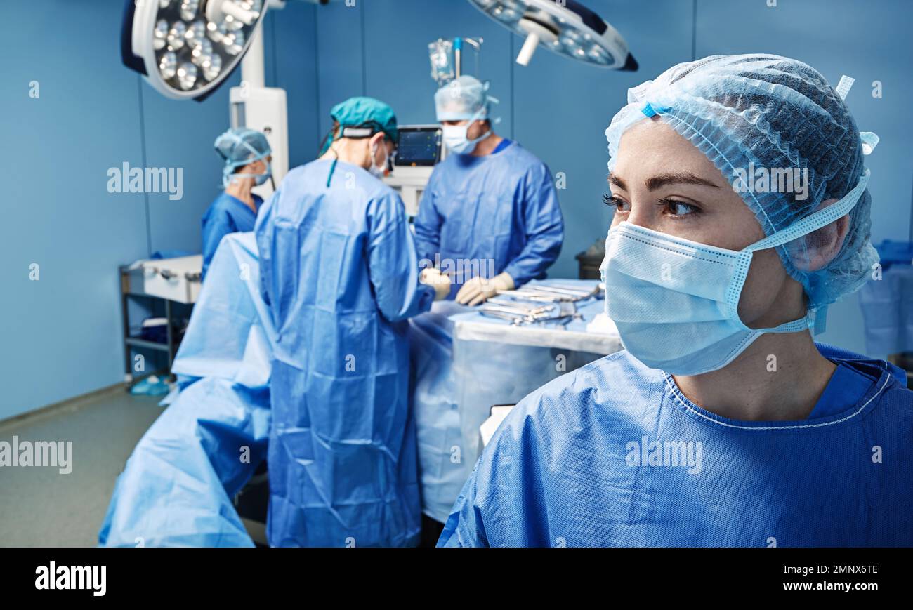 Portrait der Operationsschwester in Schutzuniform und Gesichtsmaske auf der Operationsstation mit Operationsteam. Operationskrankenschwester Stockfoto