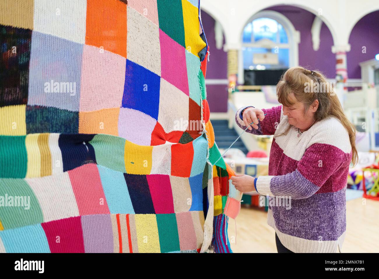 NUR REDAKTIONELLER GEBRAUCH Trisha Dearnley befestigt die letzten Plätze an einem 23ft m hohen Bobble-Hut, um den 20. Jahrestag des unschuldigen Big Knit in Partnerschaft mit Age UK in der Albert Hall in Nottingham zu feiern. Ausgabedatum: Dienstag, 31. Januar 2023. Stockfoto