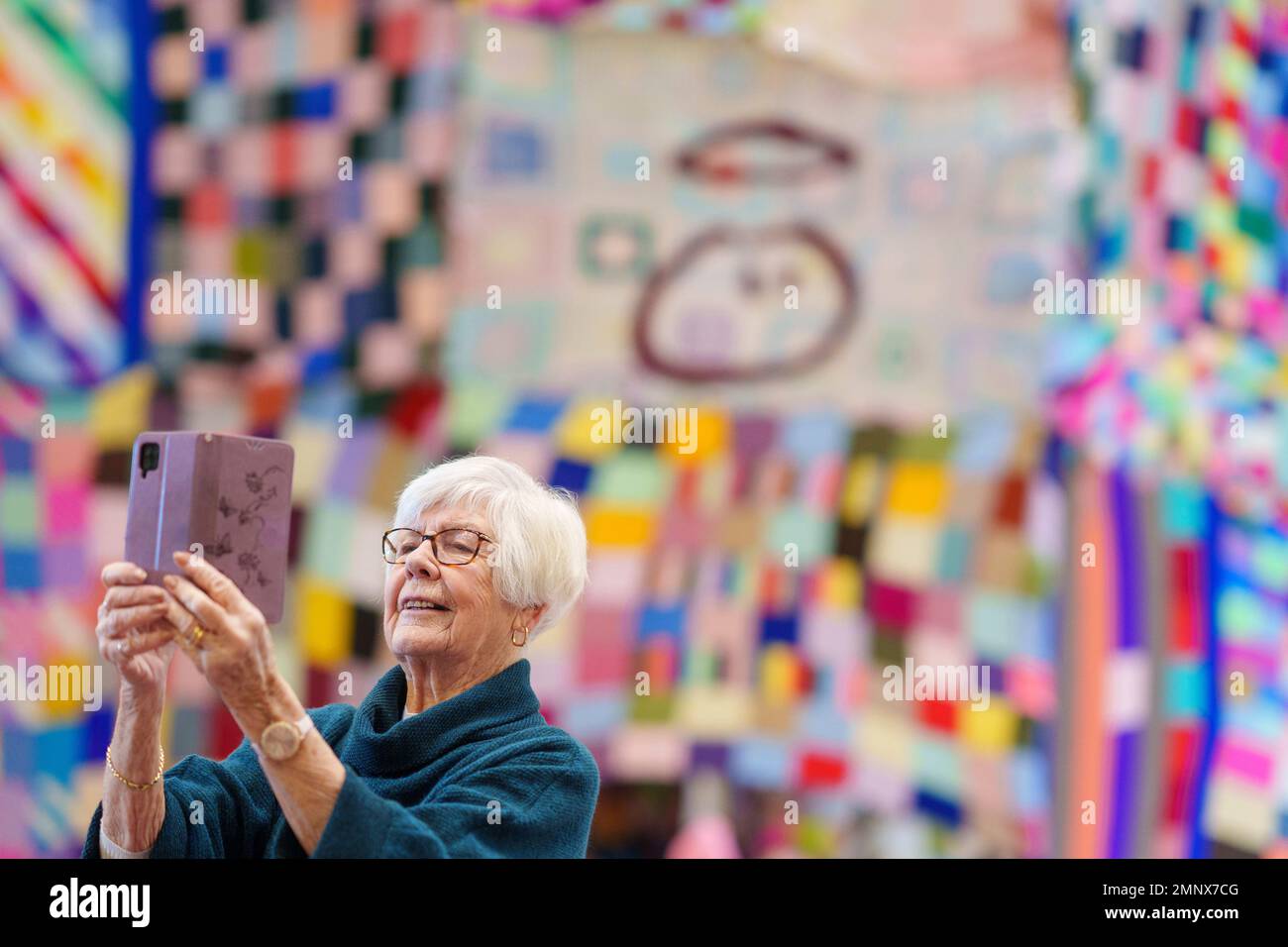 REDAKTIONELLE VERWENDUNG NUR Ein Freiwilliger macht ein Selfie mit einem 23ft m hohen Bobble-Hut, der anlässlich des 20. Jahrestages des unschuldigen Big Knit in Zusammenarbeit mit Age UK in der Albert Hall in Nottingham entworfen wurde. Ausgabedatum: Dienstag, 31. Januar 2023. Stockfoto