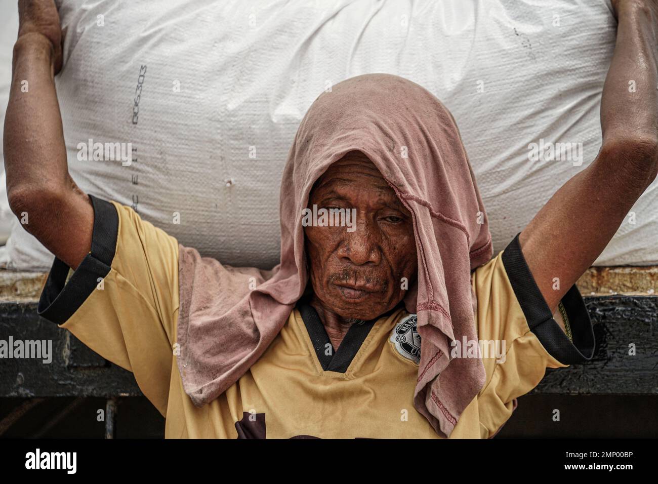 Makassar, South Sulawesi, Indonesien. 31. Januar 2023. Ein Hafenarbeiter im Hafen von Soekarno Hatta, Makassar City, heft einen schweren Sack Reis, während er ein im Hafen angedocktes Schiff beladen. (Kreditbild: © Herwin Bahar/ZUMA Press Wire) NUR REDAKTIONELLE VERWENDUNG! Nicht für den kommerziellen GEBRAUCH! Stockfoto