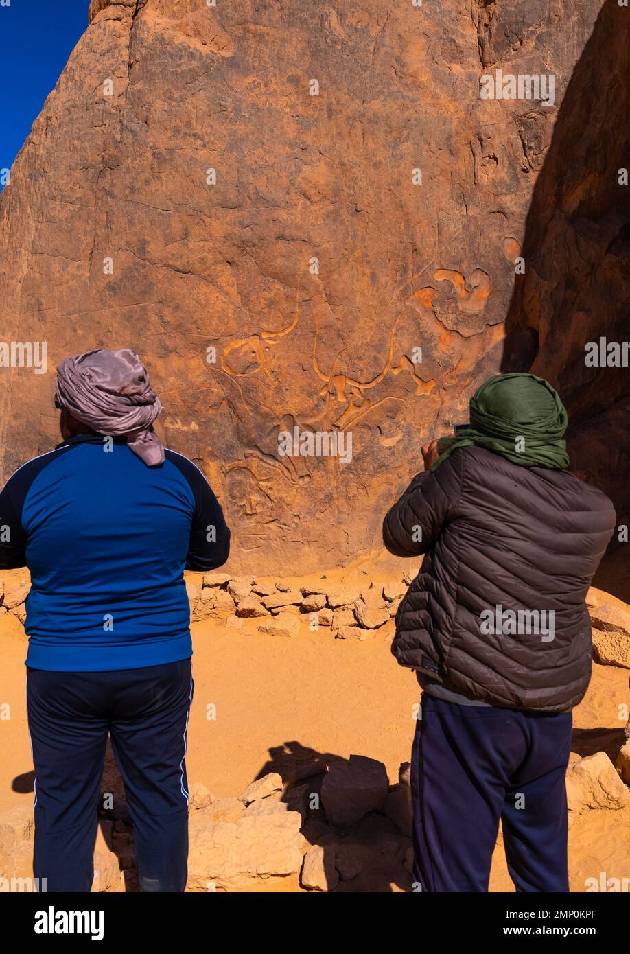 Touristen, die die Felsschnitzerei La Vache qui pleure, Nordafrika, Erg Admer, Algerien besuchen Stockfoto
