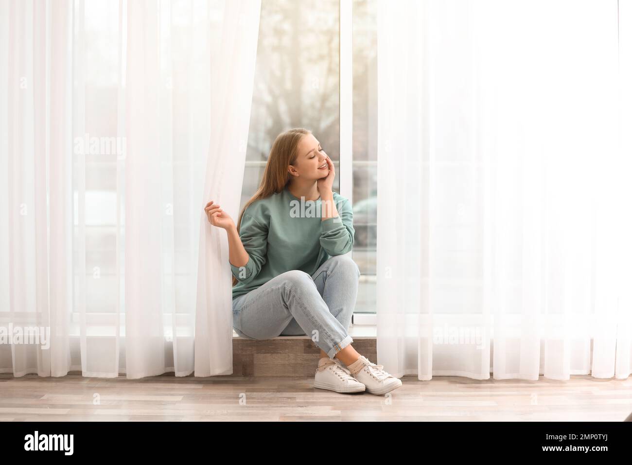 Schöne junge Frau in der Nähe der Fenster zu Hause Stockfoto