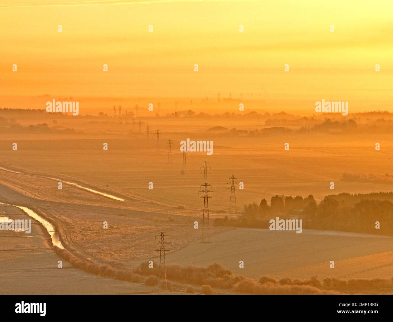 Strommasten auf einem frostigen Start in den Tag kurz nach Sonnenaufgang in Whittlesey, Cambridgeshire, während die Kälte weitergeht. Stockfoto