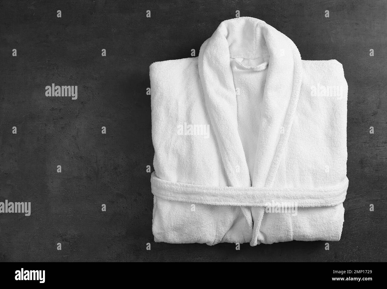 Sauberer gefalteter Bademantel auf schwarzem Steinhintergrund, Draufsicht Stockfoto