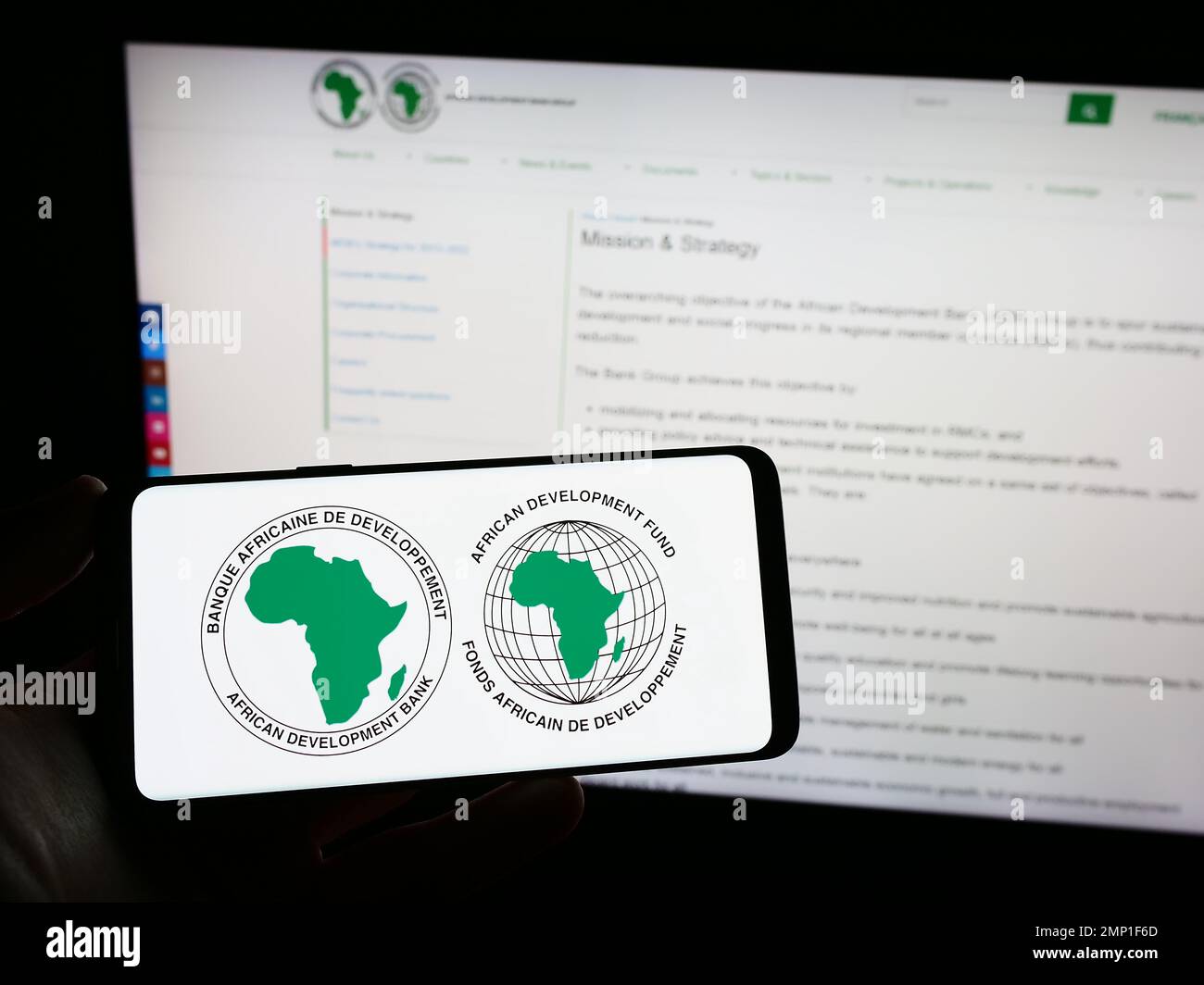 Person, die ein Smartphone mit dem Logo der African Development Bank Group (AfDB) auf dem Bildschirm vor der Website hält. Konzentrieren Sie sich auf das Display des Telefons. Stockfoto
