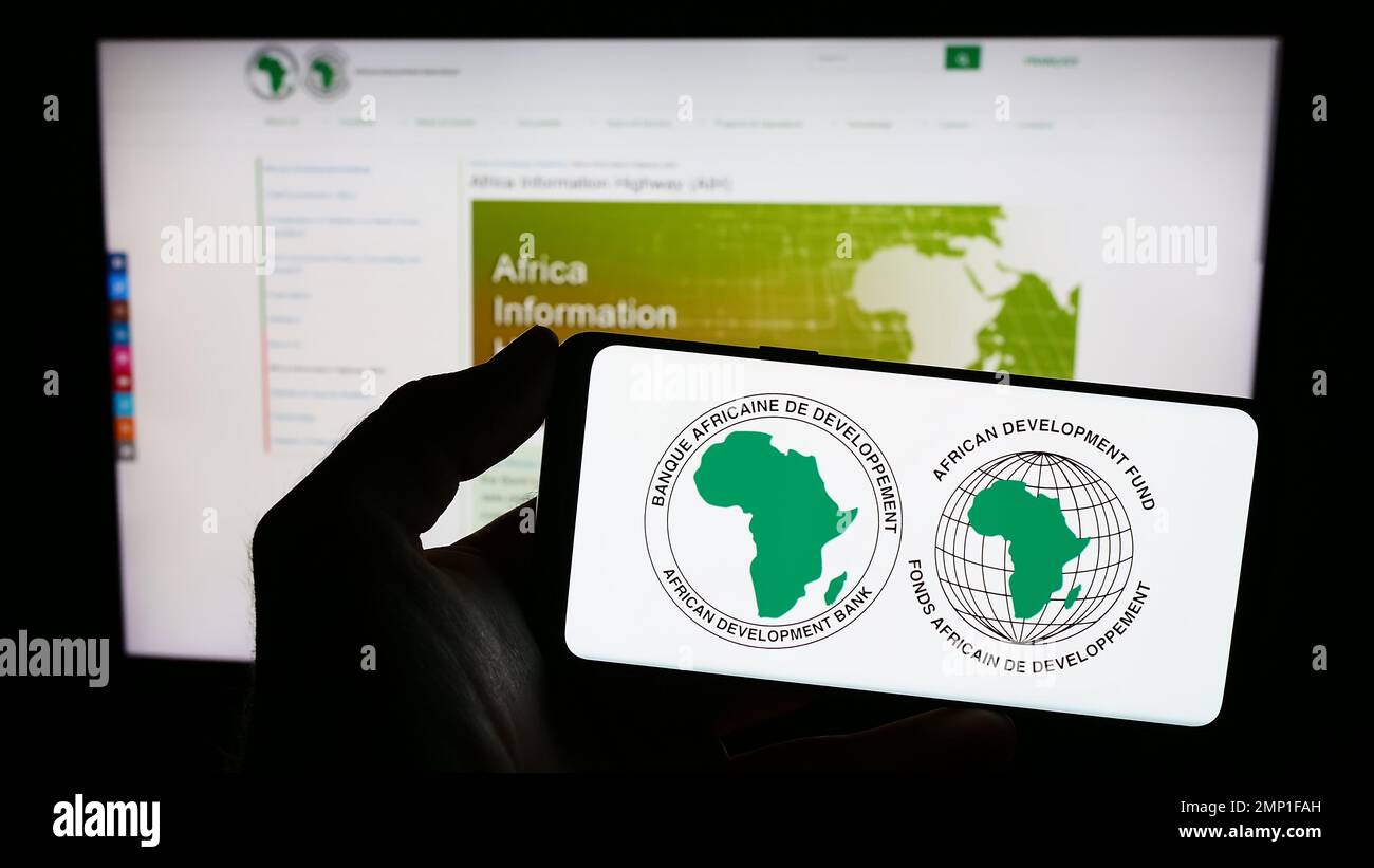 Person, die ein Mobiltelefon mit dem Logo der African Development Bank Group (AfDB) auf dem Bildschirm vor der Unternehmenswebseite hält. Konzentrieren Sie sich auf das Display des Telefons. Stockfoto