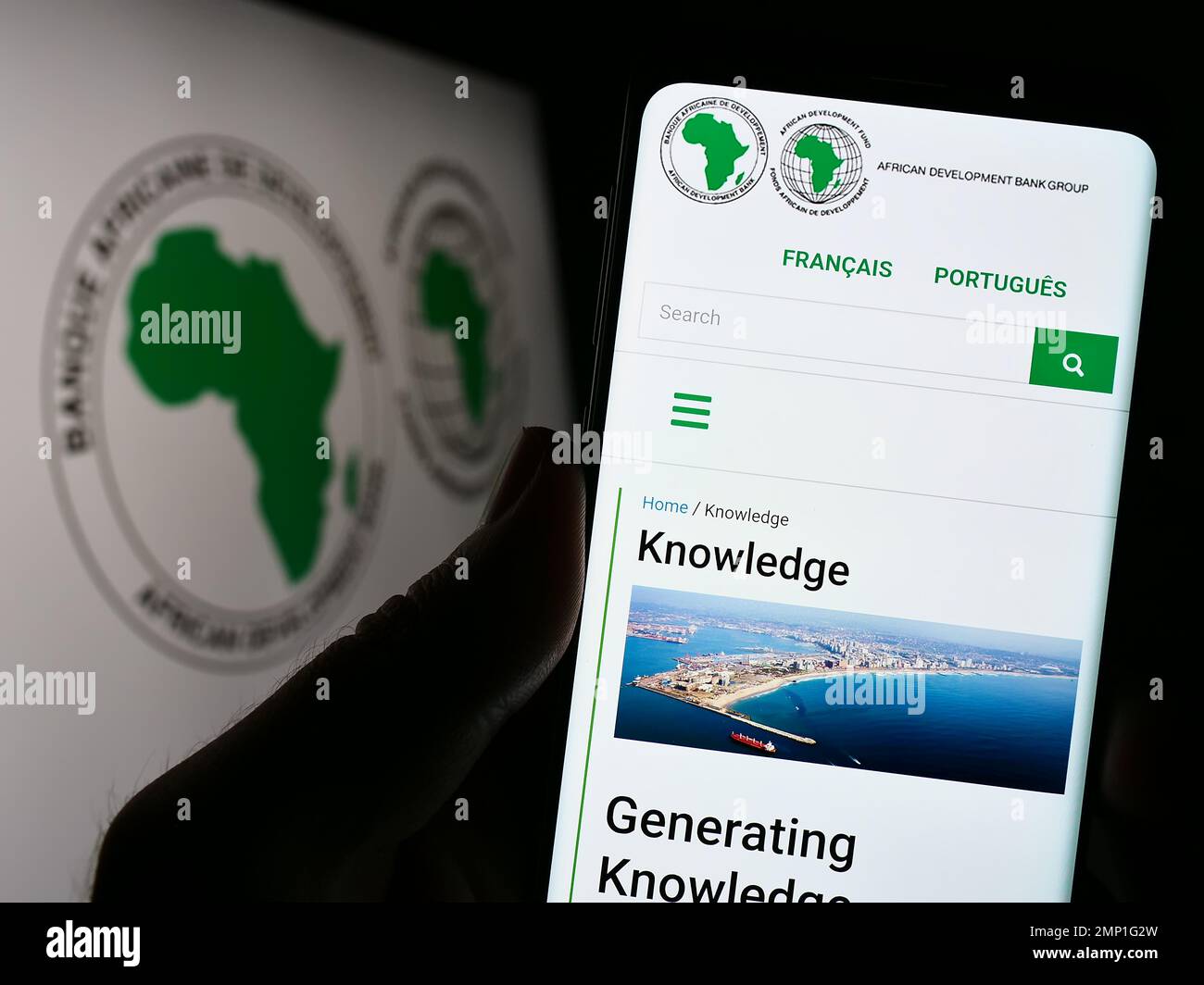 Person, die ein Mobiltelefon mit einer Webseite der African Development Bank Group (AfDB) auf dem Bildschirm vor dem Logo hält. Konzentrieren Sie sich auf die Mitte des Telefondisplays. Stockfoto