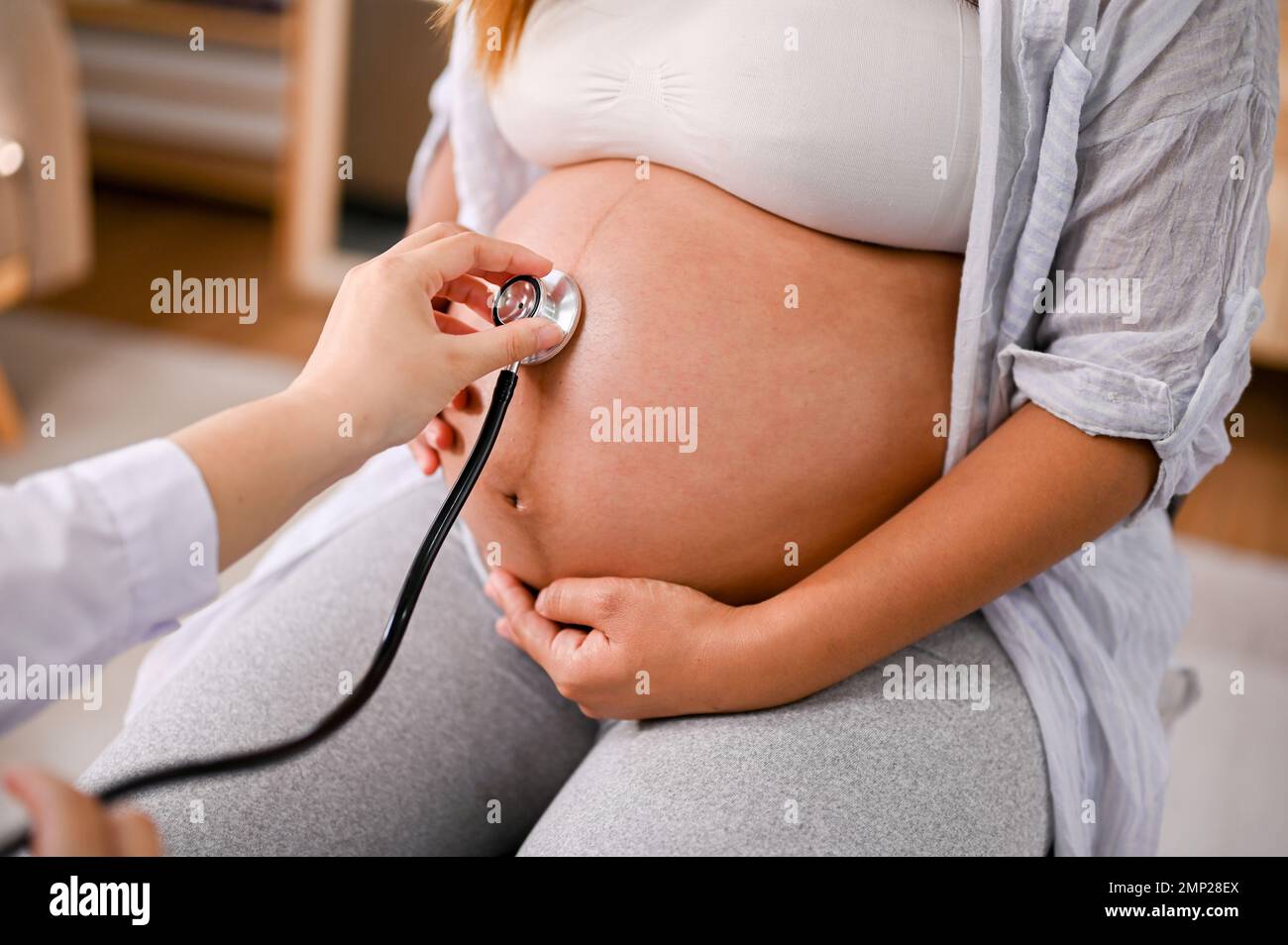 Ein professioneller Arzt, der den Herzschlag eines Babys im Bauch einer  schwangeren Frau mit Stethoskop hört. Arztliches Check-up-Konzept.  Zugeschnittenes Bild Stockfotografie - Alamy