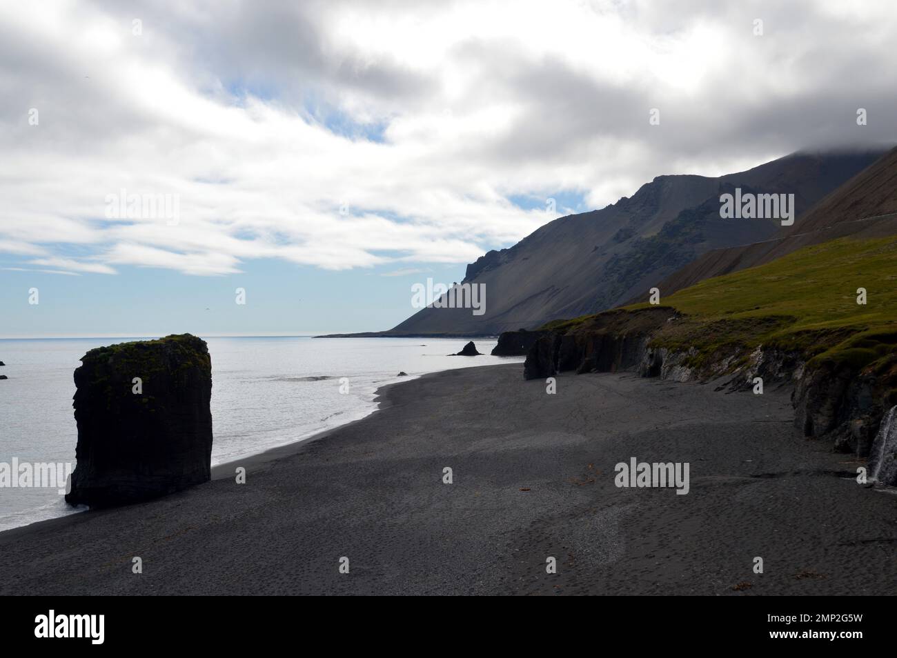 Island: Schwarzer vulkanischer Strand an der Küste nahe der Mündung des Berufjördur Fjords im Osten der Insel. Stockfoto