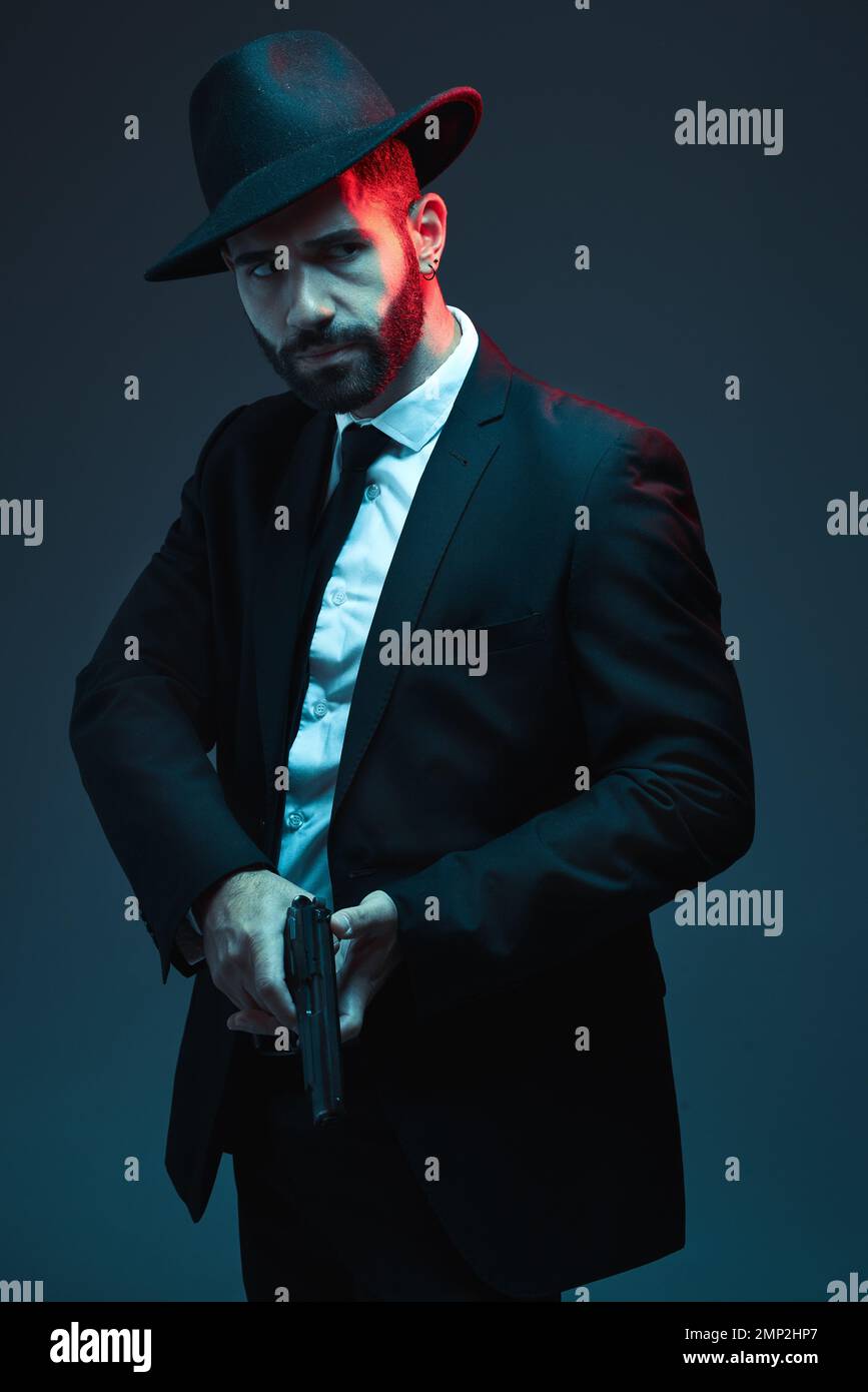 Mann, Anzug oder Waffe in dunklem Studiohintergrund in geheimer Spionin, isolierter Mafia-Führung oder Crime lord Security. Model, Gangster oder Auftragskiller Stockfoto