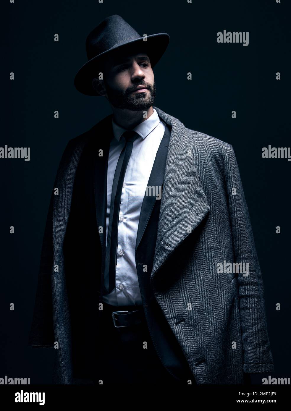 Mode, Anzug und stilvoller Mann, der an Kleidung denkt, isoliert auf dunklem Hintergrund in einem Studio. Mafia, Idee und Firmenmodell mit modisch, elegant Stockfoto