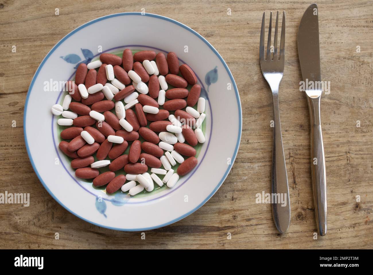 Teller mit Pillen innen und Besteck daneben für ein Gesundheitskonzept am Tisch Stockfoto