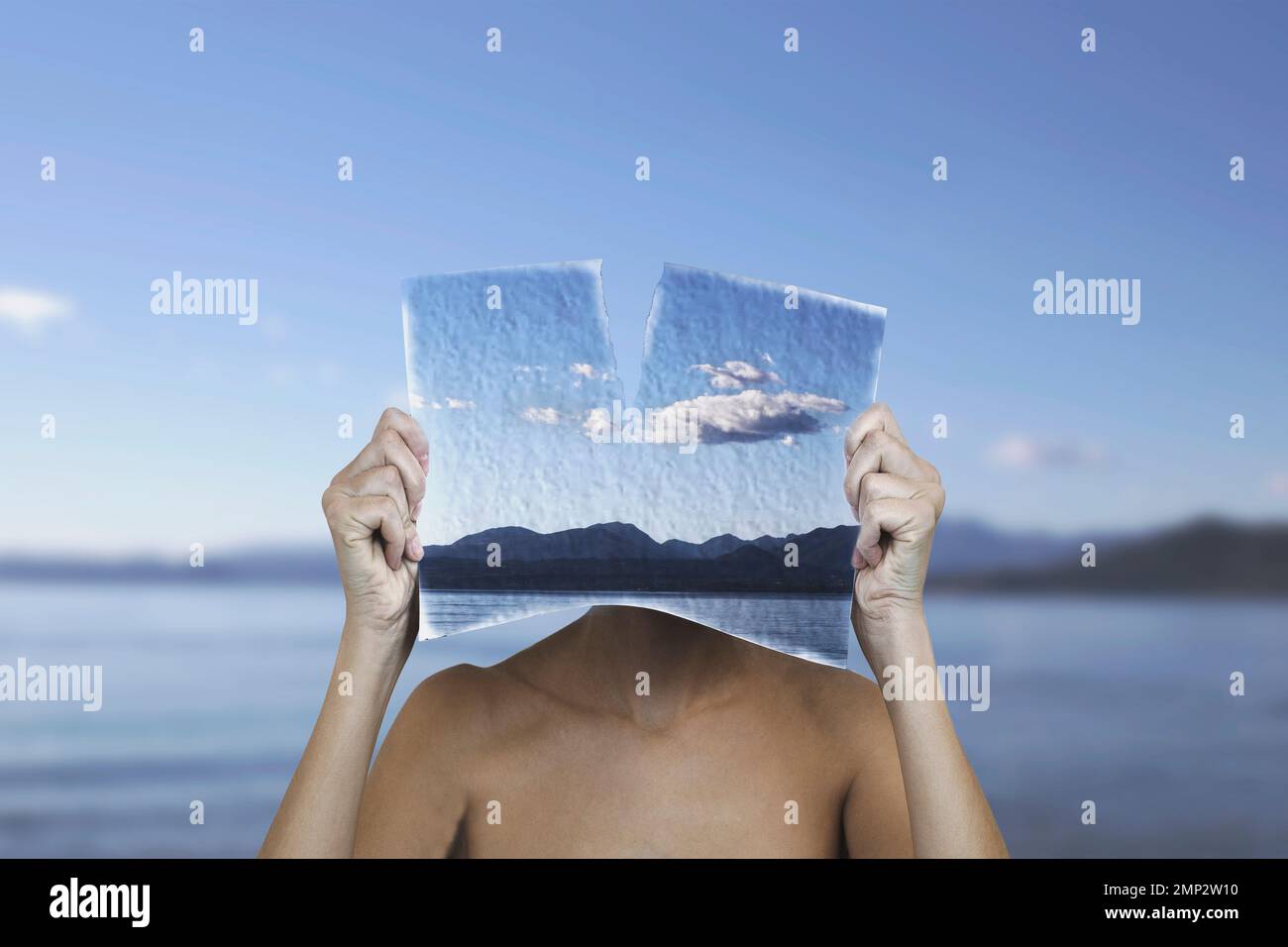 Surreale Frau mit einem bemalten Laken vor ihrem Gesicht, das der Landschaft entspricht, surreales Konzept Stockfoto