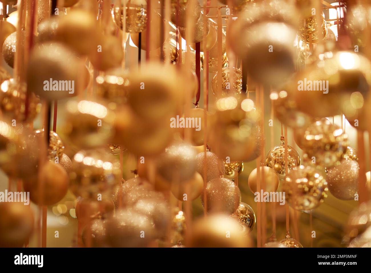 Goldene Weihnachtskugeln hängen über dem Band saisonale Weihnachtsfeier mit weichem Fokus, tropfenförmiger Fokus, ätherische magische Partydekoration Stockfoto