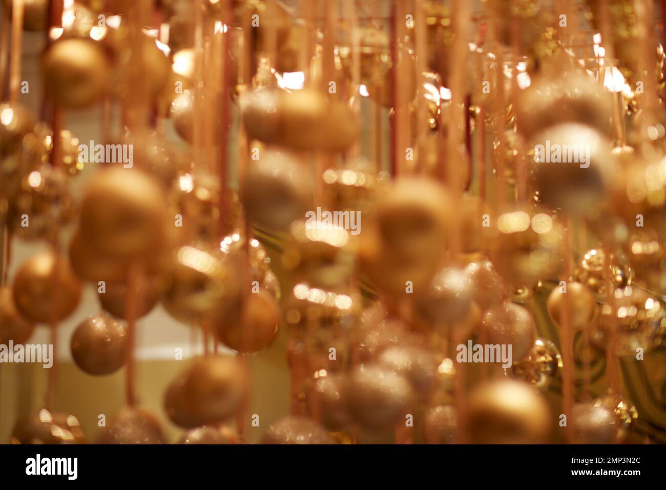 Goldene Weihnachtskugeln hängen über dem Band saisonale Weihnachtsfeier mit weichem Fokus, tropfenförmiger Fokus, ätherische magische Partydekoration Stockfoto