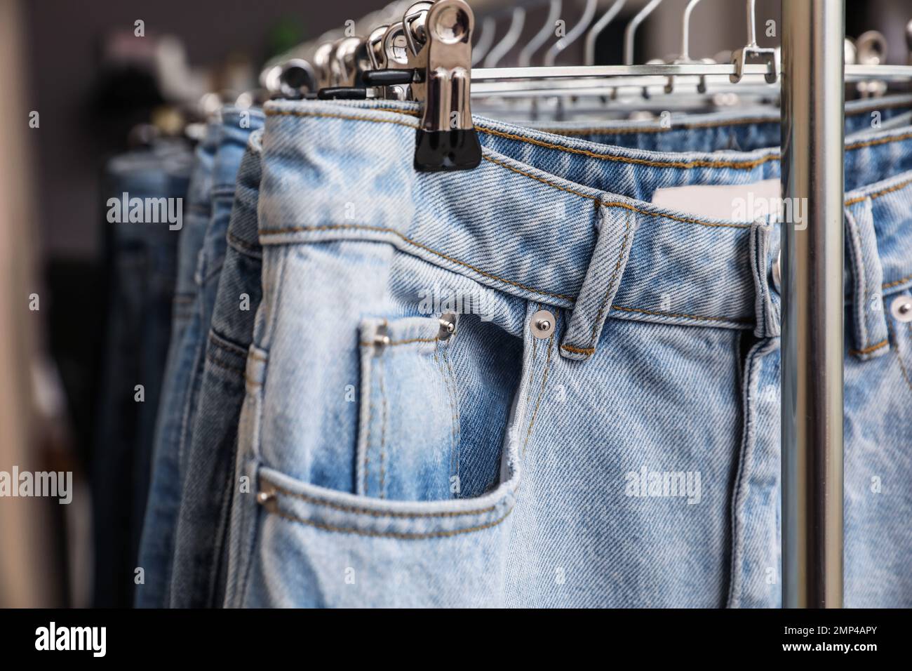 Kleiderbügel mit stylischen Jeans auf der Garderobe, Nahaufnahme Stockfoto