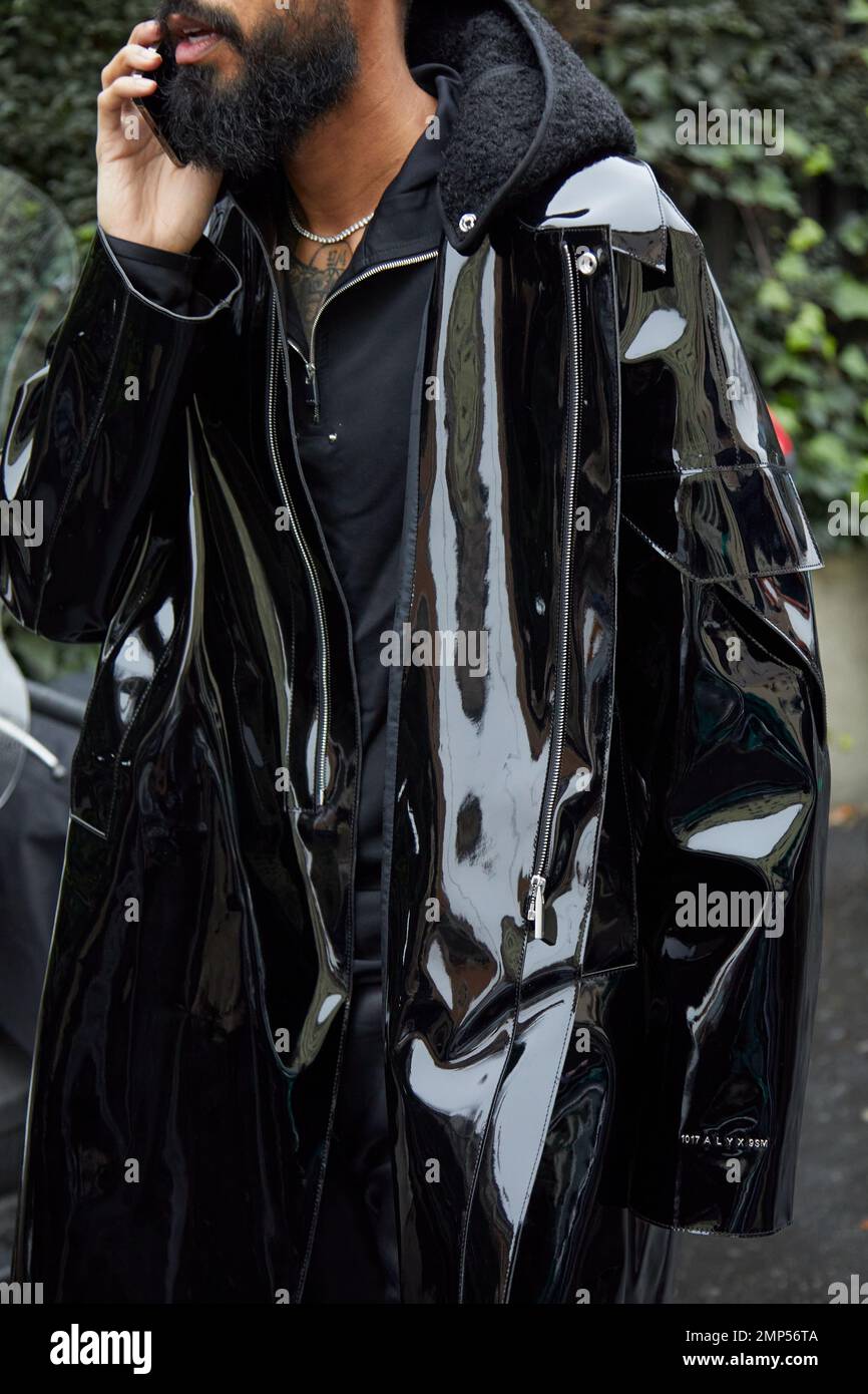 MAILAND, ITALIEN - 15. JANUAR 2023: Mann mit schwarzem, glänzendem Plastikregenmantel vor der Magliano Modenschau, Mailand Fashion Week Street Style Stockfoto
