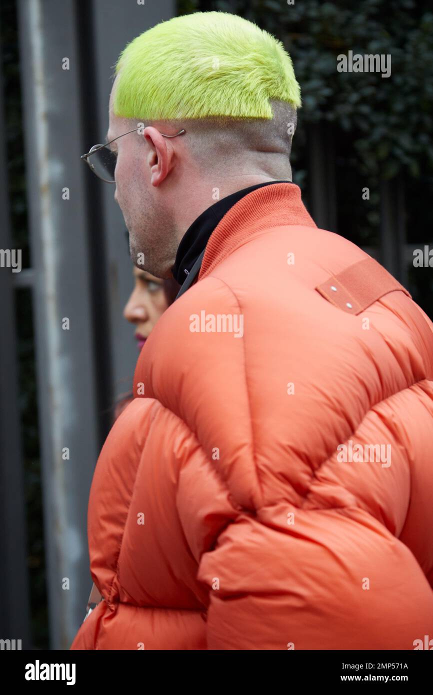 MAILAND, ITALIEN - 15. JANUAR 2023: Mann mit orangefarbener gepolsterter Jacke und gelbem Haar vor der Modenschau Magliano, Mailand Fashion Week Street Style Stockfoto