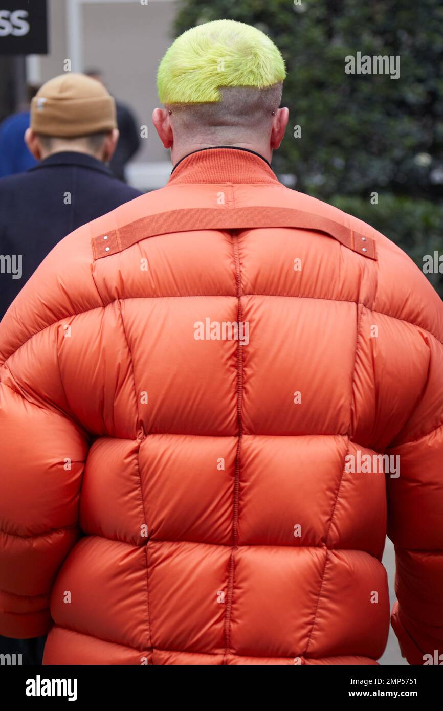 MAILAND, ITALIEN - 15. JANUAR 2023: Mann mit orangefarbener gepolsterter Jacke und gelbem Haar vor der Modenschau Magliano, Mailand Fashion Week Street Style Stockfoto