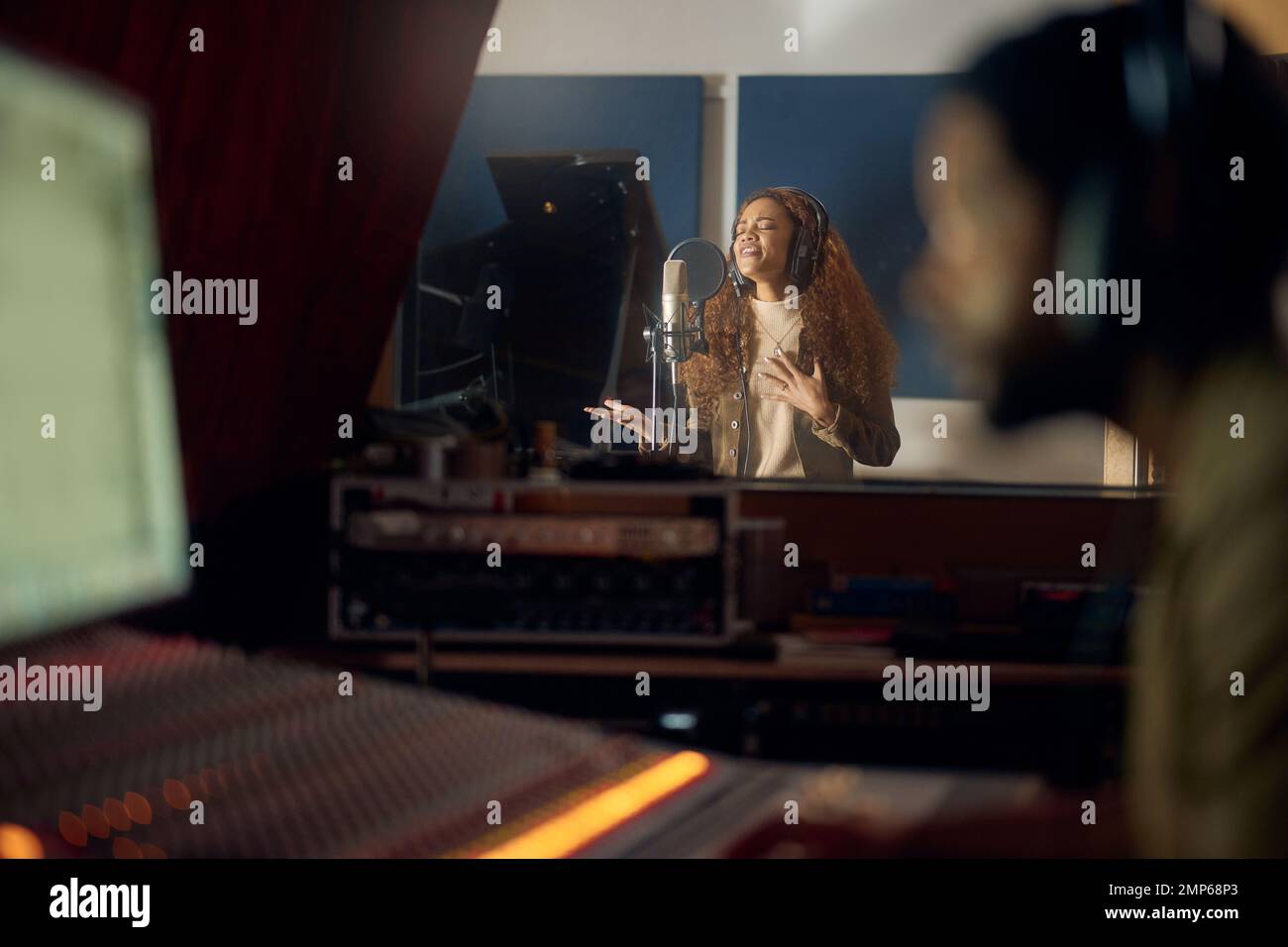 Frau, Sing- oder Studiomikrofon für Album-, Audio- oder Radiomusik-Cover in der Nachtproduktion. Sänger, Künstler oder Musiker mit Produzent Stockfoto