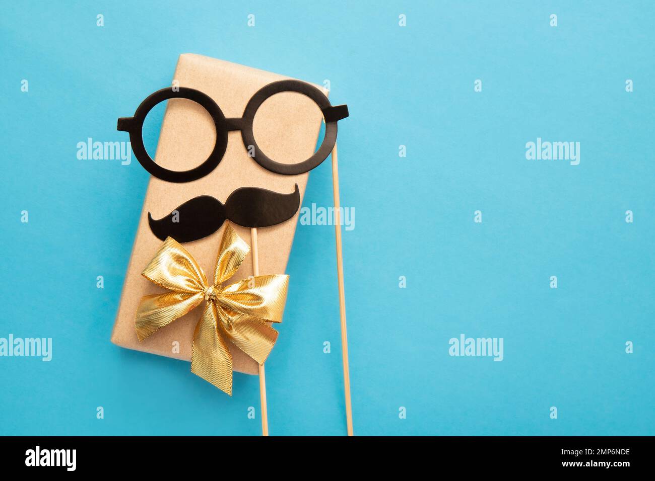 Flacher Blick auf das vollgepackte Geschenk des Vaters mit Schnurrbart und Brille auf blauem Hintergrund, viel Platz für Kopien. Lustiges Grußkartenmodell. Stockfoto