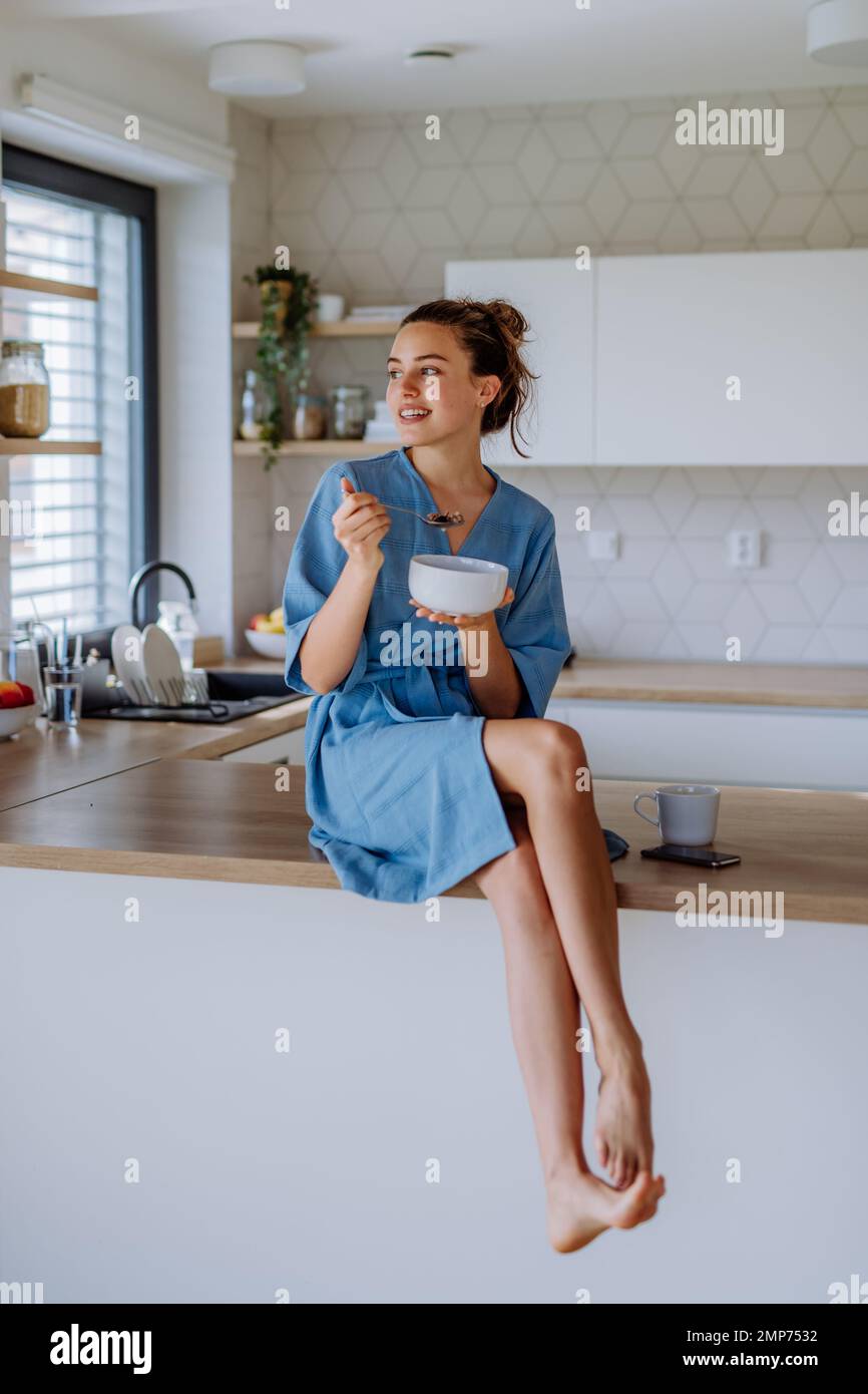 Junge Frau isst Müsli zum Frühstück in ihrer Küche, Morgenroutine und gesundes Lebensstil-Konzept. Stockfoto