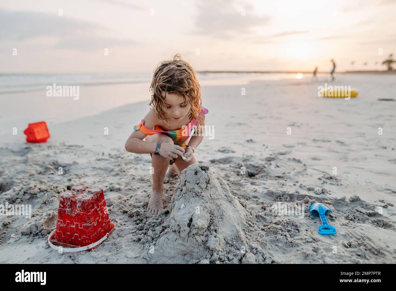 Kleines Mädchen, das am Strand spielt, Sandburg baut. Stockfoto
