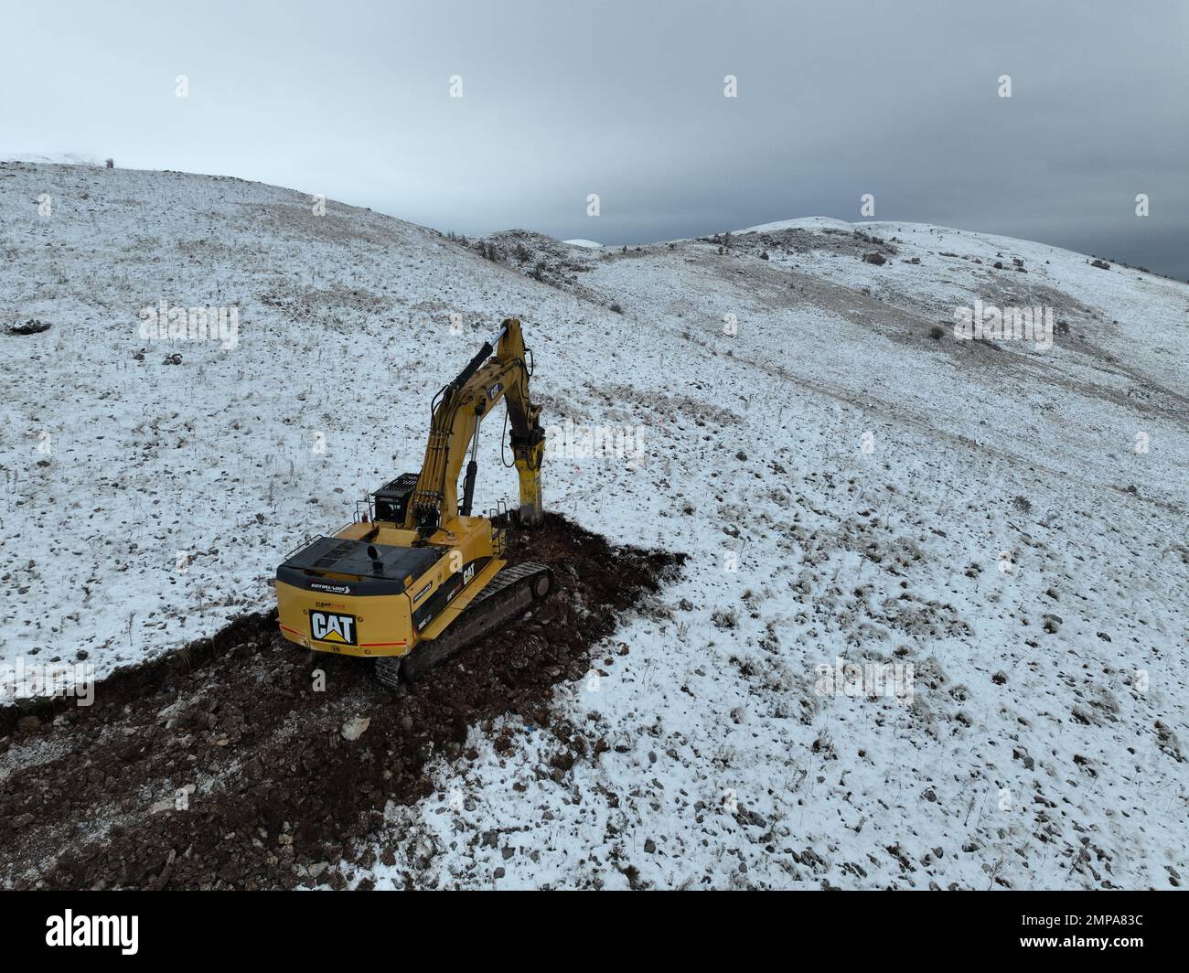 Der Hydraulikbagger mit Hydraulikhammer arbeitet auf dem Berg mit Schnee und Nebel. Stockfoto