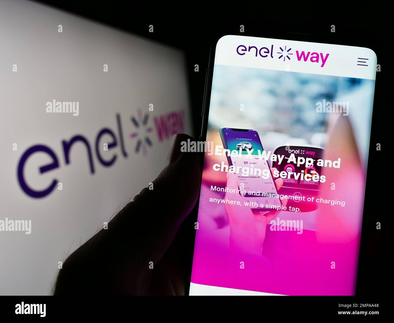 Person, die ein Mobiltelefon mit der Webseite des italienischen Elektromobilitätsunternehmens Enel X Way auf dem Bildschirm mit Logo hält. Konzentrieren Sie sich auf die Mitte des Telefondisplays. Stockfoto