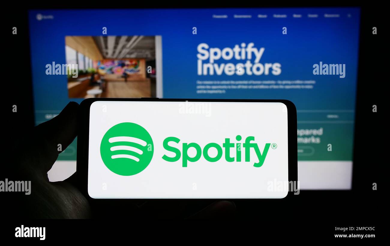 Person, die ein Mobiltelefon mit dem Logo des Musik-Streaming-Unternehmens Spotify Technology S.A. auf dem Bildschirm vor der Webseite hält. Konzentrieren Sie sich auf das Display des Telefons. Stockfoto