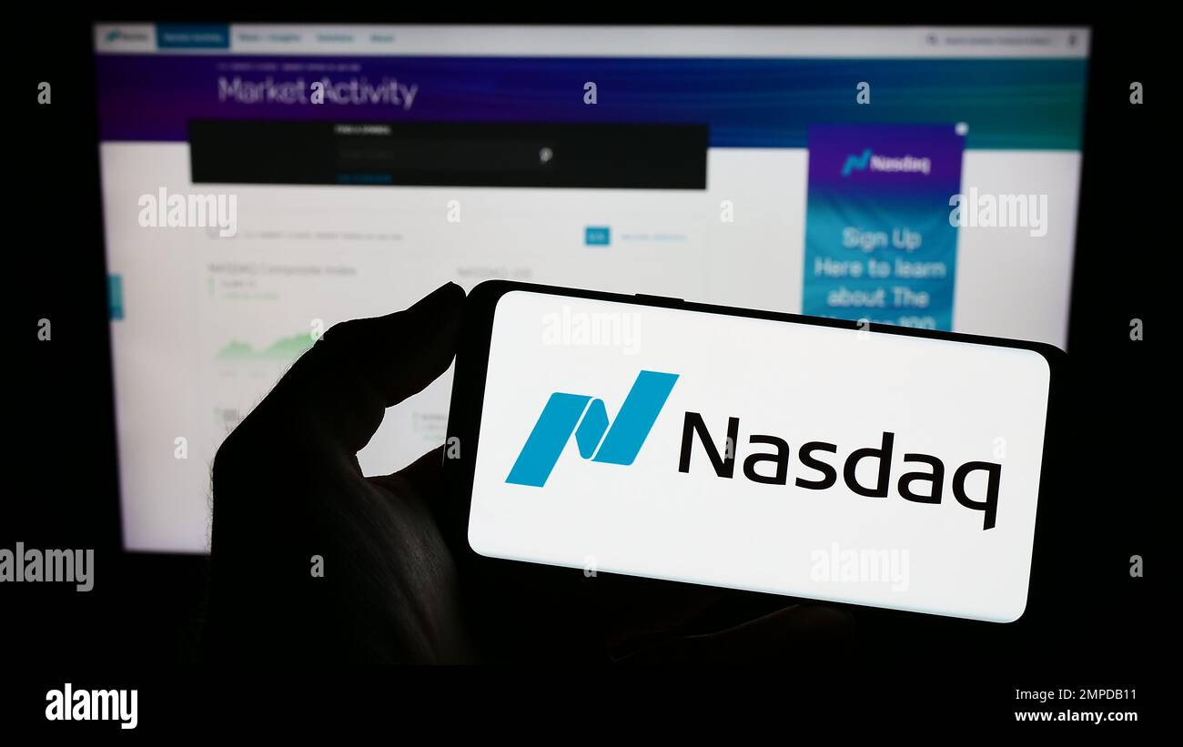 Person, die ein Mobiltelefon mit dem Logo von American Stock Exchange Nasdaq auf dem Bildschirm vor der Unternehmenswebseite hält. Konzentrieren Sie sich auf das Display des Telefons. Stockfoto