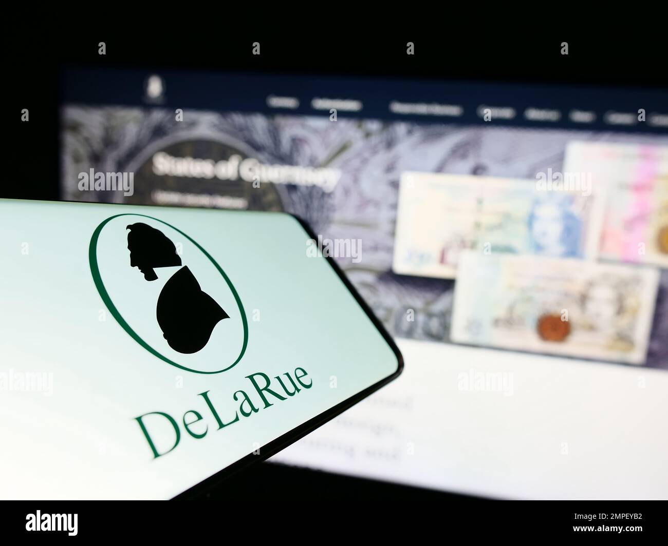 Mobiltelefon mit Logo des britischen Banknotenproduzenten De La Rue plc auf dem Bildschirm vor der Business-Website. Fokus auf die Mitte rechts des Telefondisplays. Stockfoto