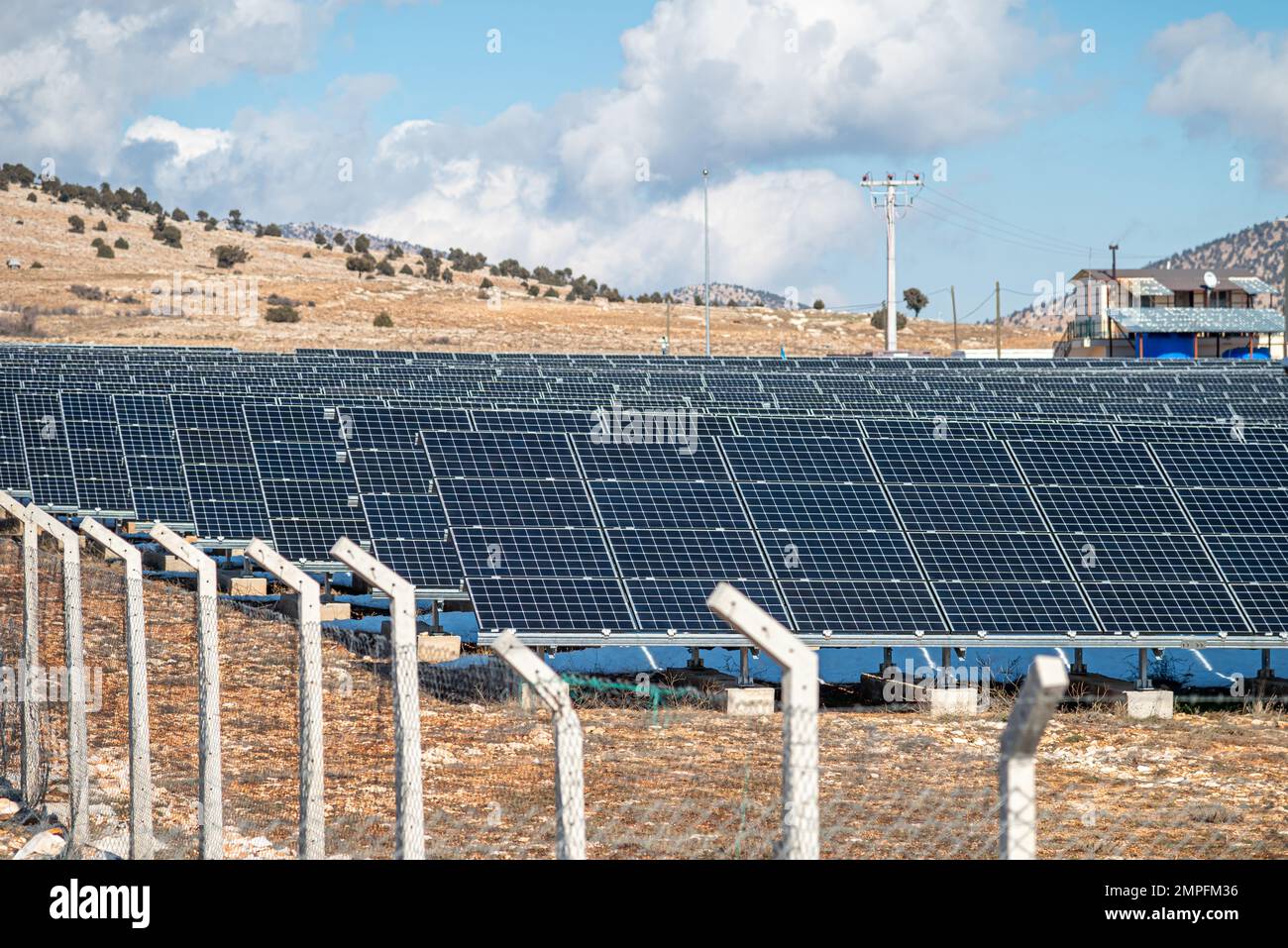 Solarfeld mit eingezäunten Sonnenkollektoren bei Sonnenuntergang Stockfoto