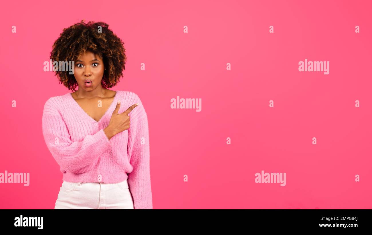 Fröhliche, geschockte junge schwarze, lockige Dame, die mit dem Finger auf die Kopierfläche zeigt, empfiehlt Werbung und Angebot Stockfoto
