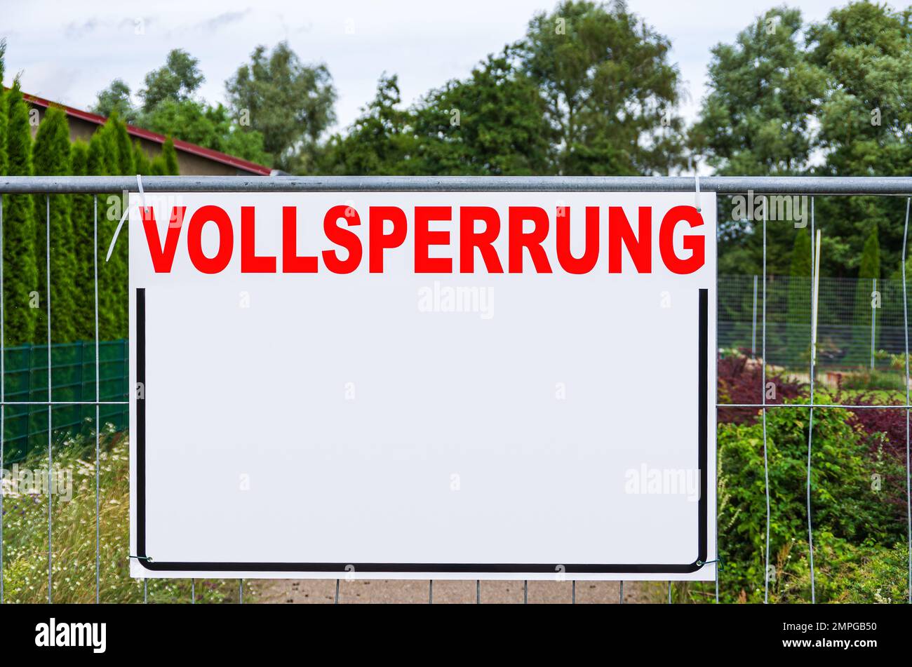 Eine rechteckige Tafel mit viel freiem Textplatz mit dem Wort VOLLSPERRUNG (Full Closure) auf einem Bauzaun. Stockfoto