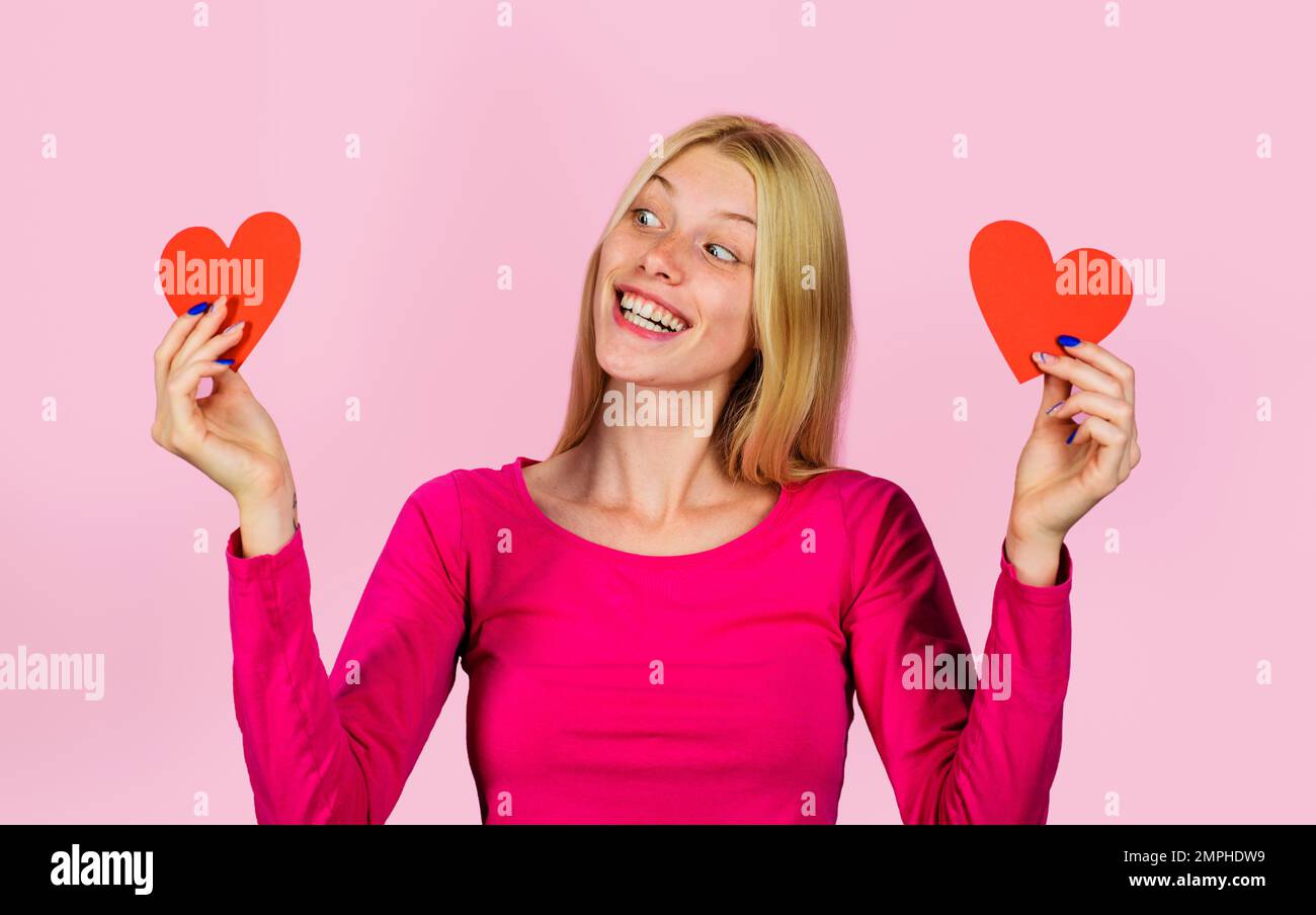 Valentinstag-Feier. Blondes Mädchen mit zwei roten Papierherzen in den Händen. Beziehungen. Stockfoto