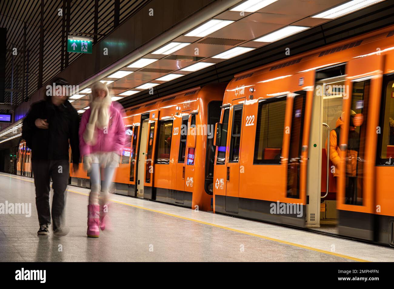 Unscharfe Bewegungen von Menschen, die den orangefarbenen U-Bahn-Zug in der U-Bahn-Station Hakaniemi, Helsinki, Finnland, verlassen Stockfoto
