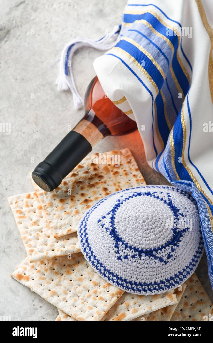 Das Konzept der Pessachstunde. Matzah, roter Koscher und Walnuss. Traditionelles jüdisches Brot Matzah, Kippah und Tallit auf altem Betonhintergrund. Pas Stockfoto