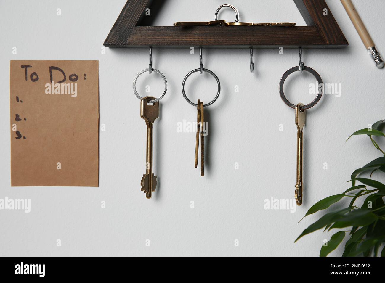 Schlüsselhalter aus Holz und Aufgabenliste an hellgrauen Innenwänden Stockfoto