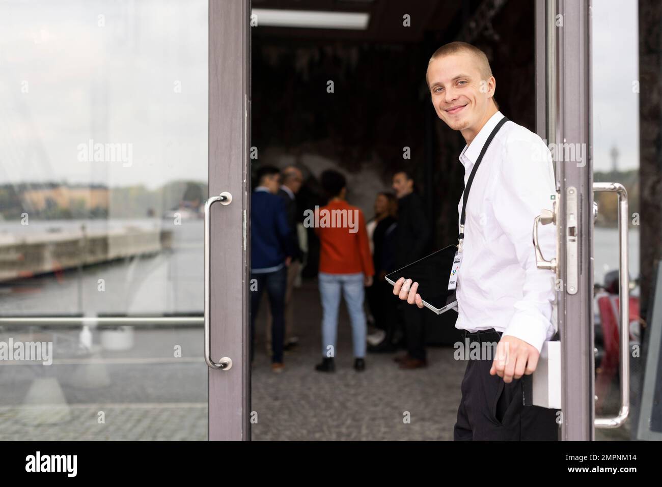 Porträt eines lächelnden jungen Geschäftsmanns, der vor der Tür des Convention Centers steht Stockfoto