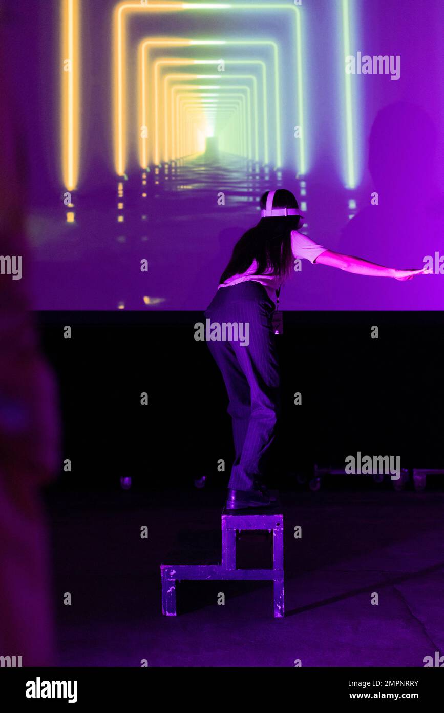 Geschäftsfrau, die auf der Leiter des Messezentrums auf die Projektionsleinwand schaut Stockfoto