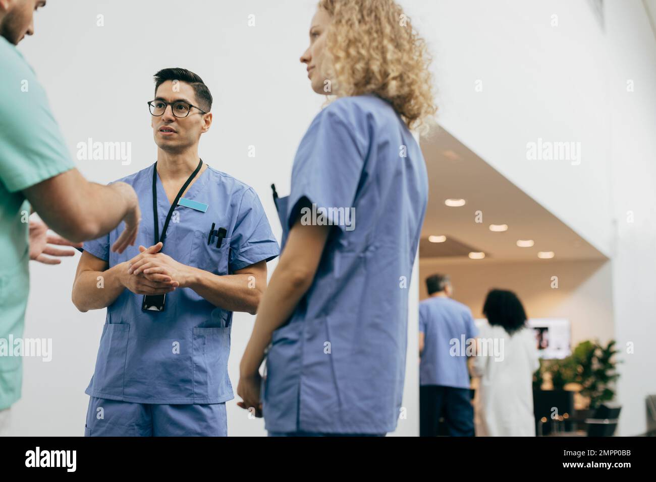 Männliche und weibliche Mitarbeiter im Gesundheitswesen diskutieren mit Kollegen im Krankenhaus Stockfoto