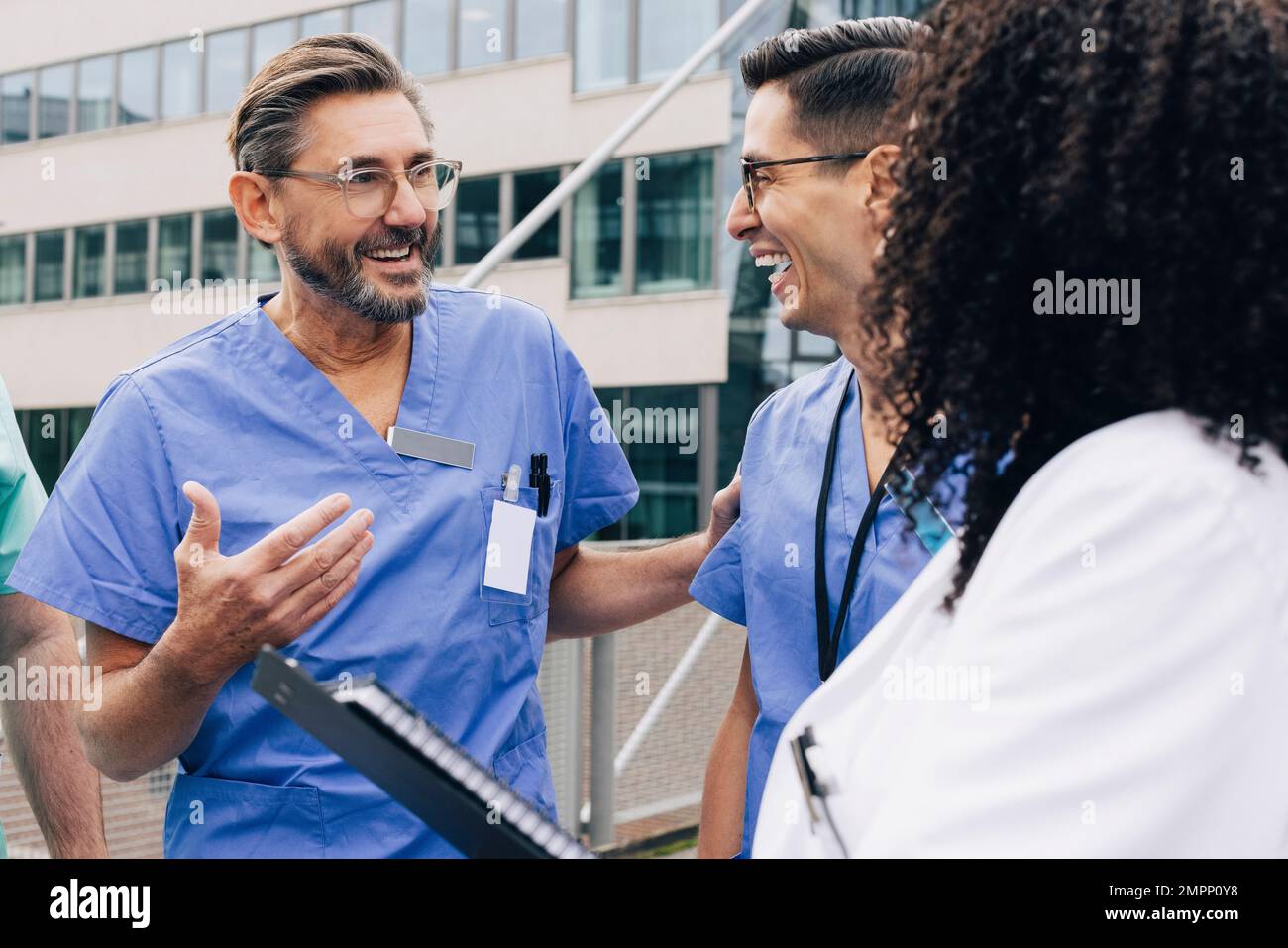 Glückliche männliche Arztgeste im Gespräch mit dem Krankenhauspersonal Stockfoto