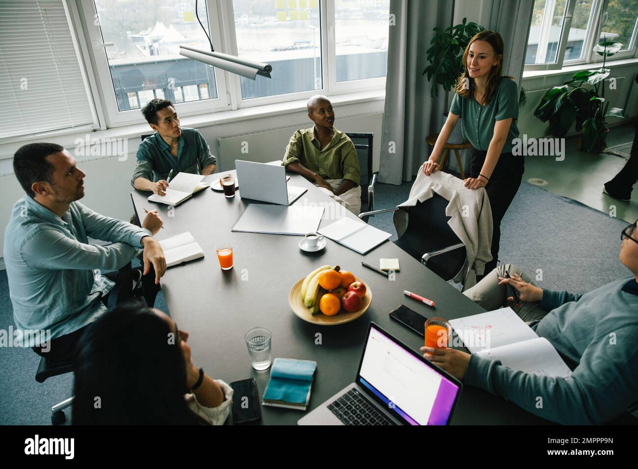 Geschäftsfrau, die in einer Brainstorming-Sitzung mit Kollegen verschiedener Rassen am Schreibtisch im Büro diskutiert Stockfoto
